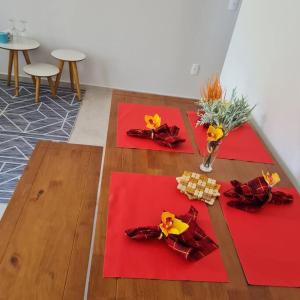 three red napkins on a table with flowers on it at A JÓIA de Itapoá a Passos da Praia in Itapoa