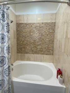 a white tub in a bathroom with a shower curtain at Entire 2 Bed apartment in Allentown
