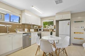 a kitchen with white cabinets and a table and chairs at Beautiful Mountain Townhouse Entire home to yourself in Beerwah