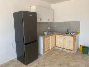 a kitchen with a black refrigerator and wooden cabinets at Beach houses Lost paradise in Mouamla