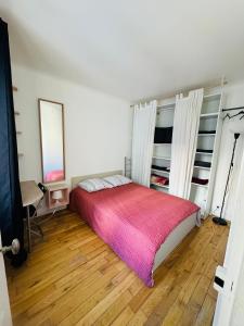 um quarto com uma cama com um cobertor rosa em Stationnement Gratuit, 3mn du Métro, Parfait pour Télétravailler em Maisons-Alfort
