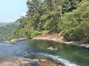 two people swimming in a river in the jungle at Princess of Dickoya Homestay in Hatton