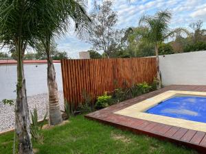 un patio trasero con piscina y una valla de madera en Casa con piscina climatizada, en Ciudad de la Costa