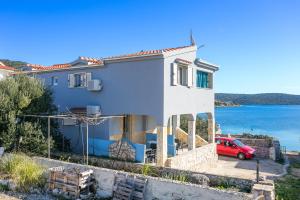 a white house with a red car in front of it at Apartments by the sea Sevid, Trogir - 4287 in Sevid