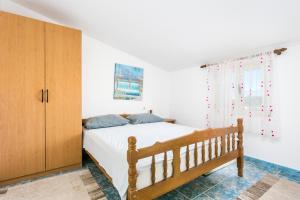 a bedroom with a bed and a wooden cabinet at Apartments by the sea Sevid, Trogir - 4287 in Sevid