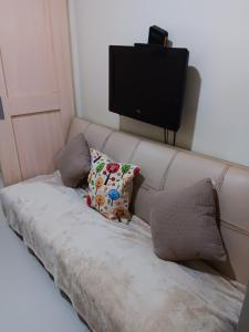 a couch with two pillows and a flat screen tv at October Homes, Field Residences, Sucat, Parañaque, Airport Express in Manila