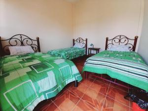 2 Betten in einem Zimmer mit grünen und weißen Decken in der Unterkunft Hospedaje Matita - Torotoro in Torotoro