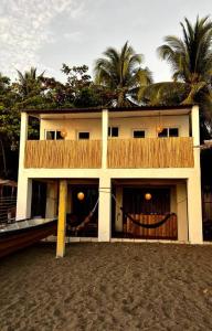 a house on the beach with palm trees behind it at Surf House Mizata in Santa María Mizata