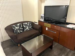 ein Wohnzimmer mit einem Stuhl und einem Flachbild-TV in der Unterkunft Hotel Pareo (Adult Only) in Kōbe