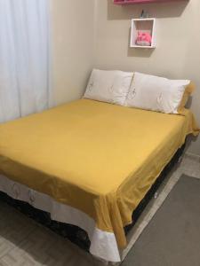 Bett mit gelber Tagesdecke und weißen Kissen in der Unterkunft Aluguel festival de Parintins in Parintins