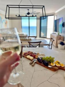 una persona che tiene un bicchiere di vino accanto a un tavolo con cibo di Phoenix X 1403 condo a Orange Beach