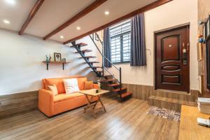 an orange couch in a living room with a staircase at Shanghai Hills&XING 4456 Homestay in Shanghai