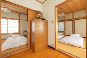 1 dormitorio con 2 camas y un espejo grande en Kalik House, en Nozawa Onsen