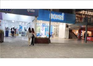 two people walking through a shopping mall with a store at Plaza Libertad in Santiago del Estero