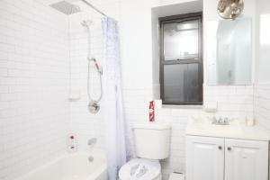 a white bathroom with a toilet and a sink at Comfy Guest House in Hell's Kitchen in New York