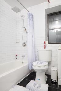a white bathroom with a toilet and a bath tub at Comfy Guest House in Hell's Kitchen in New York