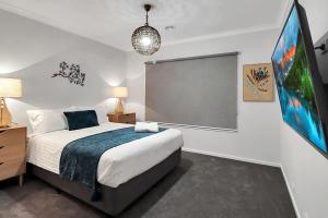 a bedroom with a large bed and a flat screen tv at Retreat on Bedajanawa in Geelong