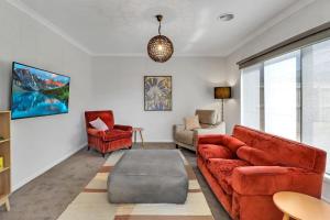 sala de estar con sofá rojo y sillas en Retreat on Bedajanawa, en Geelong