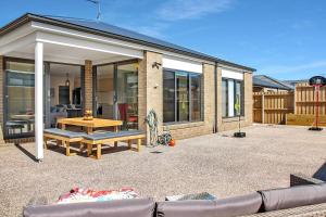 uma casa com um pátio com uma mesa e um banco em Retreat on Bedajanawa em Geelong