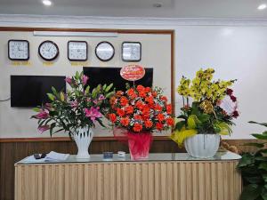 zwei Vasen Blumen auf einem Tresen in der Unterkunft Hoàng Gia Hotel Royal 