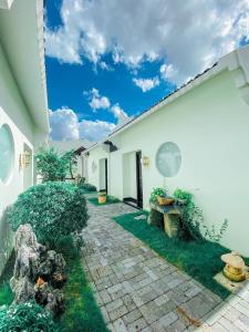 a courtyard of a white building with a stone pathway at Khách Sạn The Rice Cái Bè in Cai Be