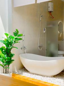 baño con bañera blanca y planta en OsCo Paviliun en Timuran