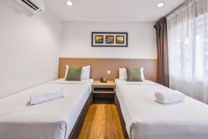 two beds in a room with a desk at Hotel Pudu Plaza Kuala Lumpur in Kuala Lumpur