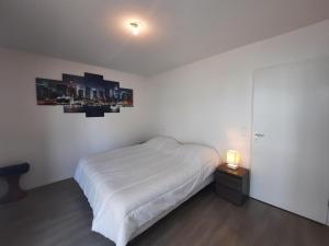 ein weißes Schlafzimmer mit einem Bett und einer Lampe auf einem Tisch in der Unterkunft Appartement Anglet, 2 pièces, 4 personnes - FR-1-239-1021 in Anglet