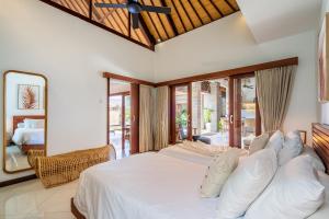 a bedroom with a large white bed with a mirror at VILLA JIWA SANUR in Sanur