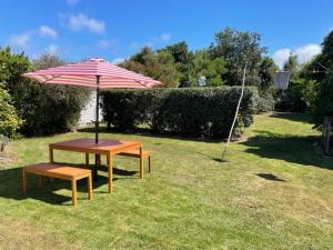a table and a bench under an umbrella at Kina Cottage in Tasman