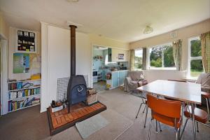 a living room with a table and a stove in it at Kina Cottage in Tasman