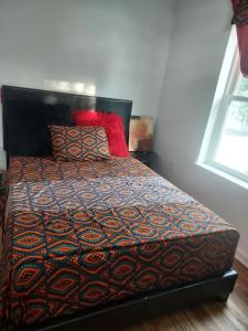 1 dormitorio con 1 cama con manta y almohadas en NGU-GI Homess, en Lebanon