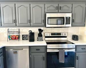 a kitchen with white cabinets and a microwave at Renovated home 10 min from FLW! in Saint Robert