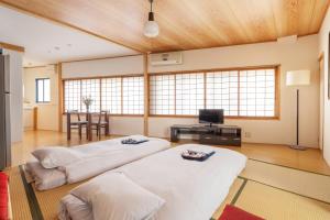 two beds in a room with a table and a television at Corner House in Nozawa Onsen