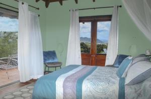 1 dormitorio con 1 cama y balcón en Spanish-style Ocean view Villa set in garden - Calypso Court villa, en Cap Estate