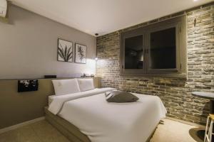 Incheon Stay Inn Hotel في انشيون: غرفة نوم بسريرين وجدار من الطوب