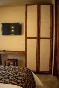1 dormitorio con 1 cama y TV en la pared en Villa Tanatli, en Pérula