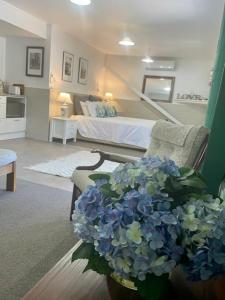 uma sala de estar com uma cama e um vaso de flores azuis em Annabells B&B em Whitianga