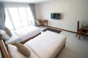 a hotel room with two beds and a tv at Nivas Chiangmai in Chiang Mai