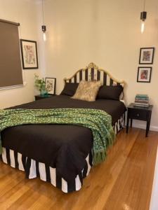 a bedroom with a large bed with a wooden floor at Evies Belmont Cottage in Geelong