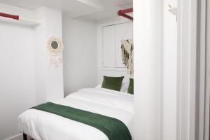 Schlafzimmer mit einem Bett mit weißer Bettwäsche und grünen Kissen in der Unterkunft Comfy Guest House in Hell's Kitchen in New York