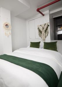 a bedroom with a large white bed with green pillows at Comfy Guest House in Hell's Kitchen in New York