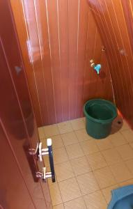 a small bathroom with a green bucket in the corner at Villa Mangrove Pulau Pahawang in Lampung
