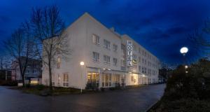 um edifício branco com um cartaz à noite em PLAZA INN Karlsruhe Nord em Karlsruhe