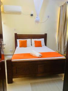 a bed with two orange pillows on top of it at 2bedroom apartment in nyali in Mombasa