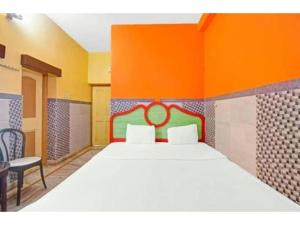 a bedroom with a large bed and an orange wall at Goroomgo Indranil Digha in Digha