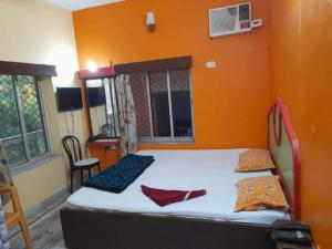a bed in a room with an orange wall at Goroomgo Indranil Digha in Digha