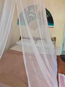 un letto con tende bianche in una stanza di AABANA Beach & Watersport Resort a Isola di Malapascua