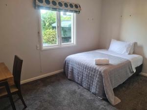 a small bedroom with a bed with a window at J&L Boarding Holiday House in Hamilton