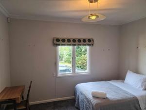 a bedroom with a bed and a window and a table at J&L Boarding Holiday House in Hamilton